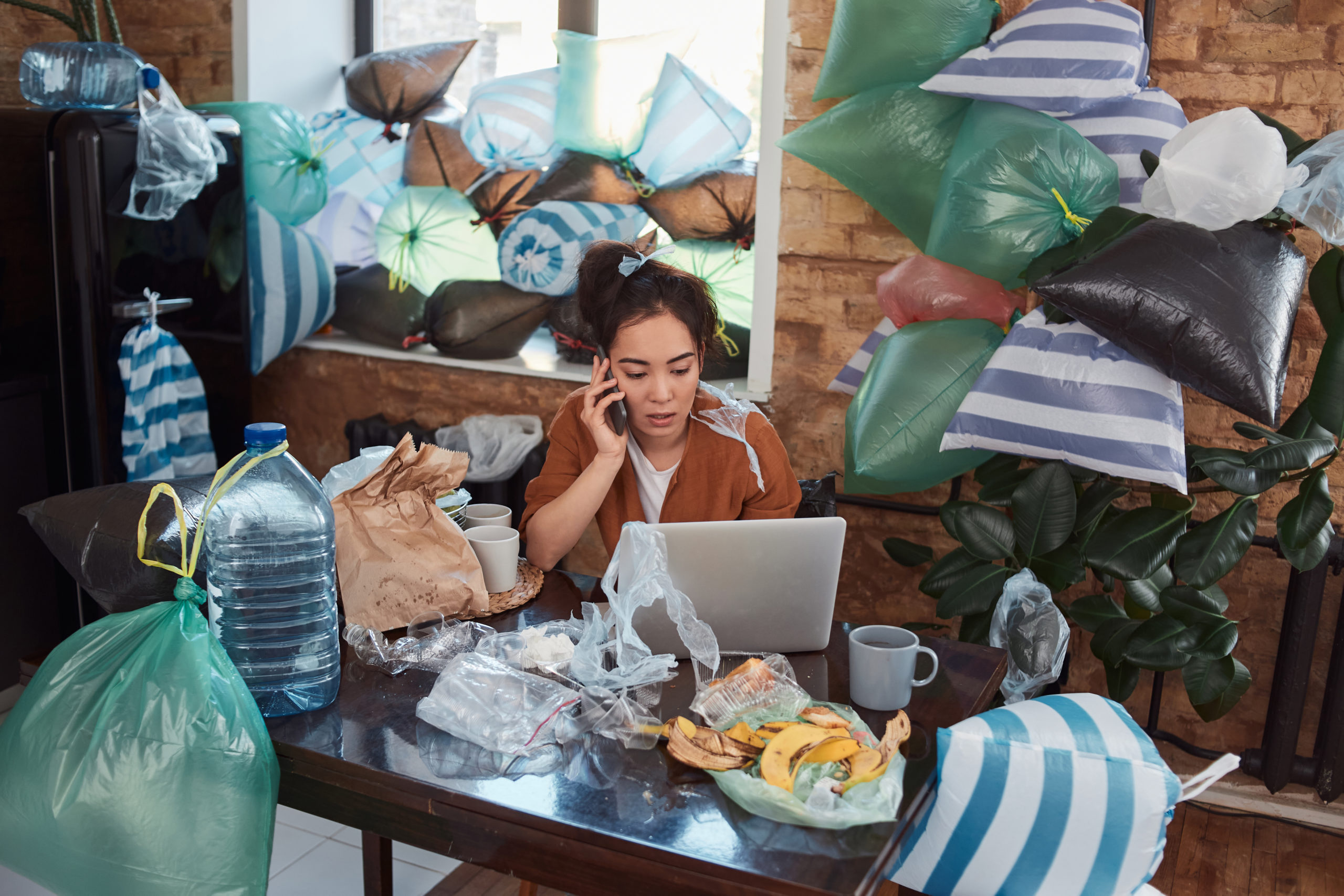A woman working on her laptop in a cluttered room