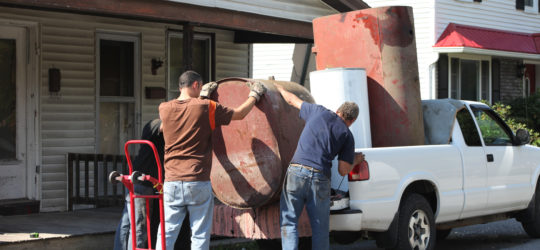 Three guys hauling away scrap metal tanks