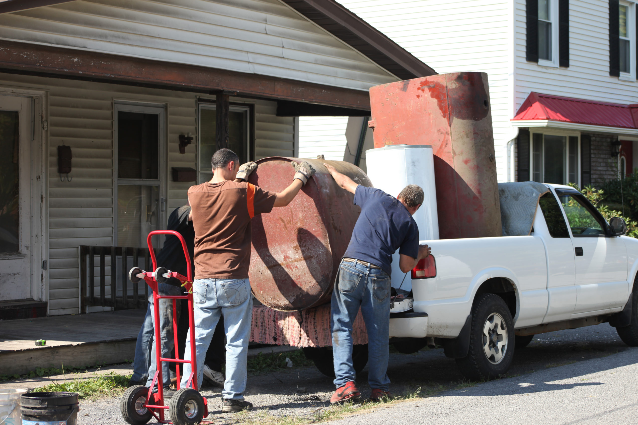 Three guys hauling away scrap metal tanks